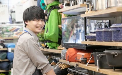 アウトドア商品の前でほほ笑む男性スタッフ